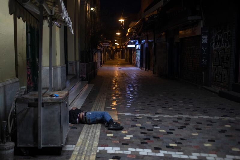 A man sleeps on a street outside shuttered shops in the Monastiraki district of Athens as lockdown measures continue to prevent the spread of the coronavirus. AP