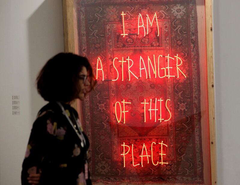 A woman stands near Turkish artist Ramazan Can's 2018 work "I am a Stranger of This Place" at Art Dubai in Dubai. AP Photo
