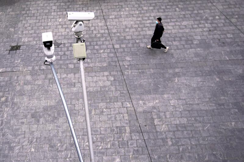 A man wearing a protective mask walks under surveillance cameras in Shanghai, China, as the country is hit by a novel coronavirus outbreak, at the Pudong financial district in Shanghai, China February 28, 2020. REUTERS/Aly Song