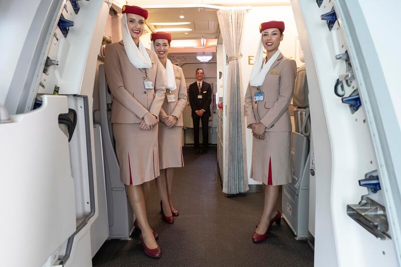 Flight attendants welcome passengers to the flight