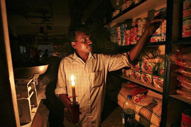A worker uses a candle in a store in Sharjah's Industrial Area 1 after a power failure.