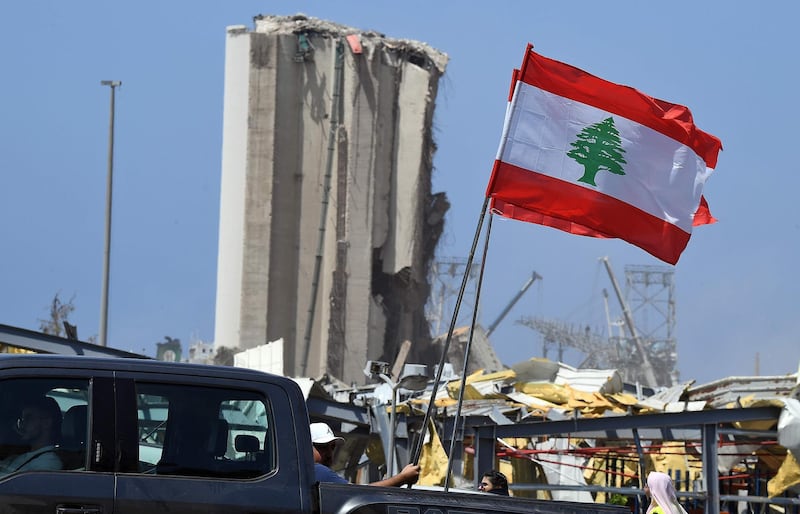 Lebanese people carry the national flag as they drive past the blast site four days after a monster explosion. AFP