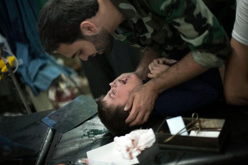 Wounded by Syrian Army shelling, a child is comforted by a Free Syrian Army fighter.