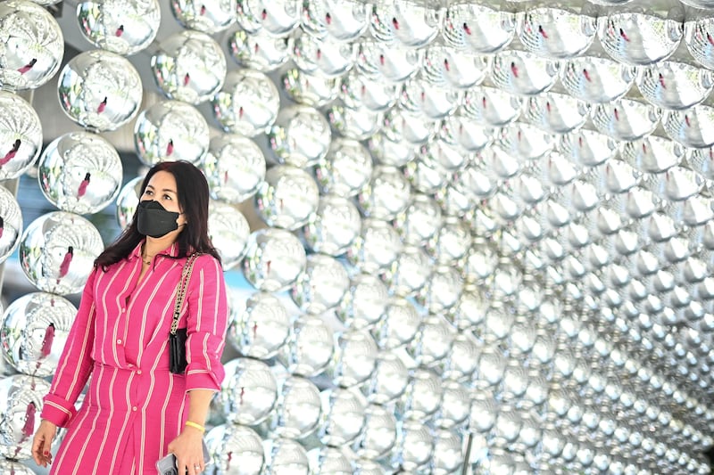 A woman walks past a decoration made of reflective balls outside a shopping mall in Bangkok. AFP