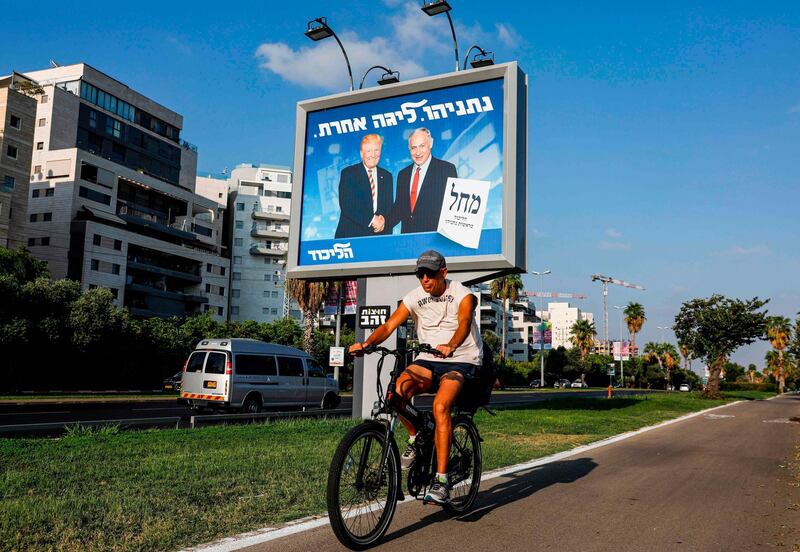 A man cycles beneath an Israeli electoral billboard for the Likud party showing US President Donald Trump shaking hands with Prime Minister Benjamin Netanyahu. AFP
