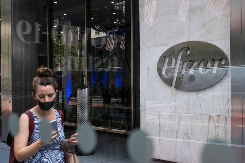 A pedestrian wearing a protective mask passes in front of Pfizer Inc. headquarters in New York, U.S., on Wednesday, July 22, 2020. U.S. health officials agreed pay $1.95 billion for 100 million doses of a vaccine made by Pfizer Inc. and BioNTech SE, the latest step in an effort to fight the coronavirus pandemic. Photographer: Jeenah Moon/Bloomberg