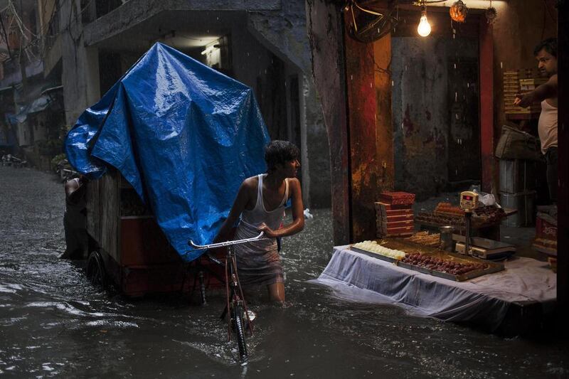 An Indian sweets vendor, right, shouts at a labourer who is pulling a cart through a street flooded due to monsoon rains in New Delhi, India. The vendor was reacting angrily since the ripples created by the cart’s movement was causing the floodwater to enter his shop. Tsering Topgyal/ AP Photo