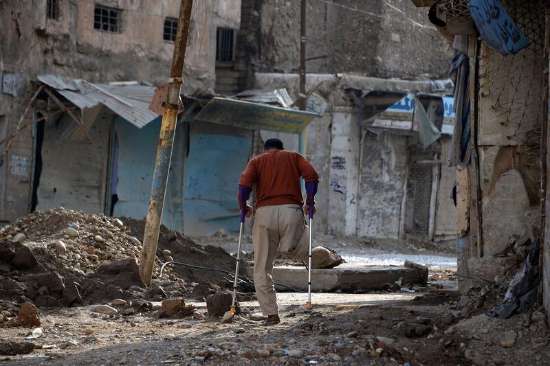 An amputee uses crutches to walk in a debris-strewn street in the old neighbourhood of Mosul in Iraq. AFP