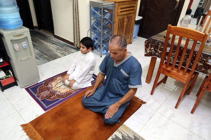 Rayan prays with his dad Yousef in the family home in Ajman. Chris Whiteoak / The National