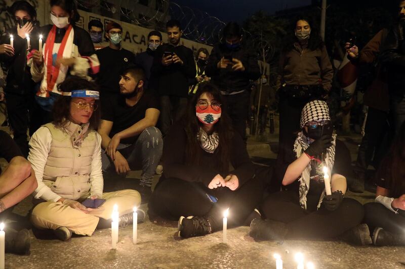 Protesters wearing protective face masks light candles during an anti-government demonstration outside the headquarters of the Lebanese central bank in Beirut.  Bloomberg