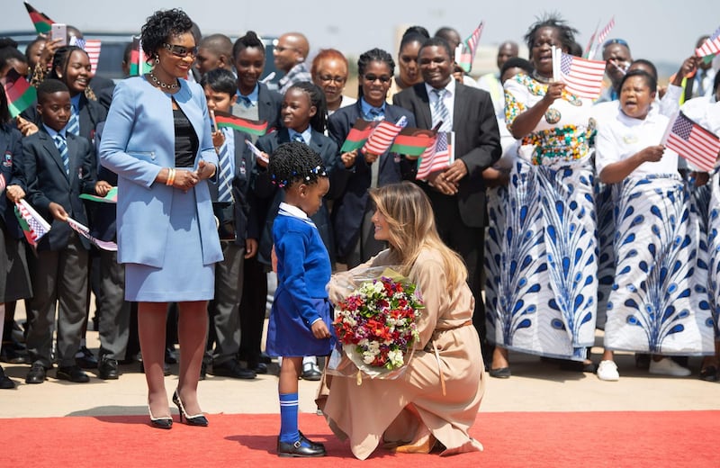 US First Lady Melania Trump receives flowers from a young girl alongside the First Lady of Malawi, Gertrude Mutharika, as she arrives at Lilongwe International Airport. Saul Loeb / AFP