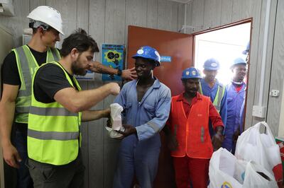 DUBAI ,  UNITED ARAB EMIRATES , JULY 3 – 2019 :- Hannes Loubser , fitness instructor with Iconic giving food packets to the DEWA construction workers after the fitness training session at the DEWA Sub Station near the International City in Dubai. ( Pawan Singh / The National ) For Lifestyle . Story by Melanie Swan