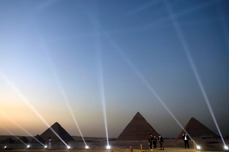 People take pictures in front of the Great Pyramids during the opening of a new restaurant called 9 Pyramids Lounge. Reuters