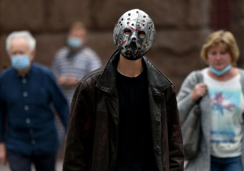 A man wearing an iron mask walks among people wearing surgical masks in the center of the Ukrainian capital of Kiev.  AFP