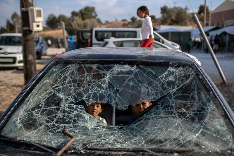 Afghan children play inside an abandoned car as refugees and migrants from the destroyed Moria camp are sheltered, near a new temporary camp, on the island of Lesbos, Greece. AP Photo
