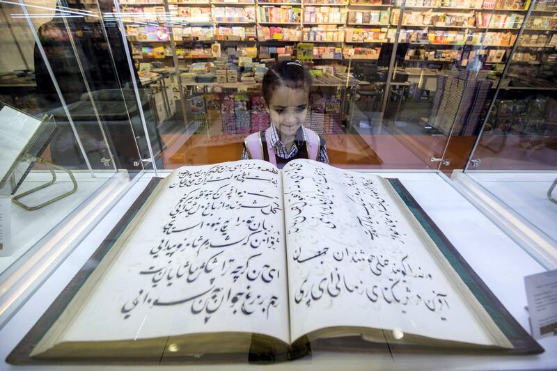 SHARJAH, UNITED ARAB EMIRATES - A girl interested at the book inside a display at The Sharjah Book Fair.  Leslie Pableo for The National