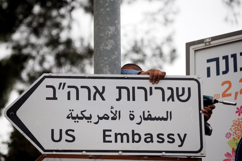 FILE PHOTO: A worker hangs a road sign directing to the U.S. embassy, in the area of the U.S. consulate in Jerusalem, May 7, 2018. REUTERS/Ronen Zvulun/File Photo