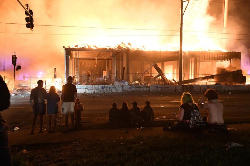 Protesters gather near the Minneapolis Police third precinct to watch a construction site burn. REUTERS