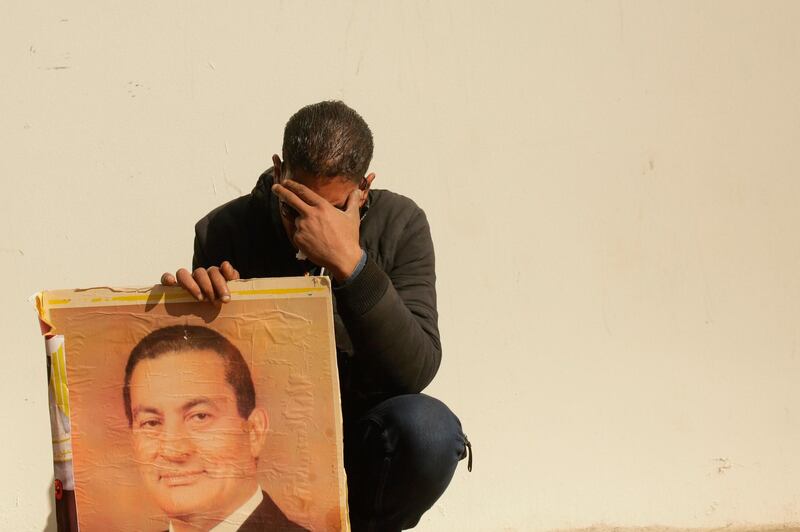 A supporter holds a photo of Egypt’s ousted President Hosni Mubarak as he weeps outside the gate of the mosque ahead of the former leader's funeral in New Cairo, Egypt. AFP