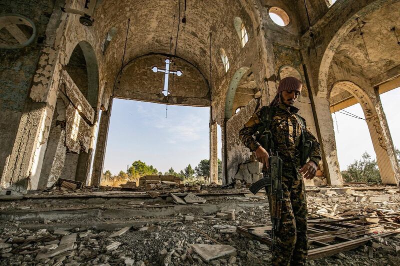 A member of the Khabour Guards (MNK) Assyrian Syrian militia, affiliated with the Syrian Democratic Forces (SDF), walks in the ruins of the Assyrian Church of the Virgin Mary, which was previously destroyed by ISIS. AFP
