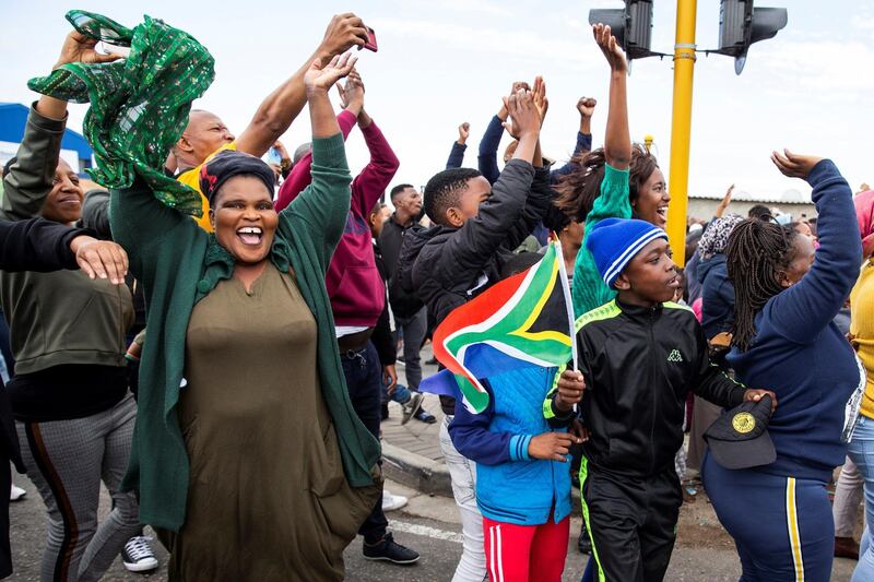 People cheer as South African Rugby World Cup winner team parades on an open top bus. AFP