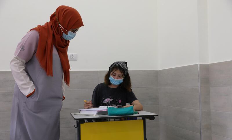A teacher helping a pupil during class at the Modern English School in the occupied West Bank city of Nablus.  EPA