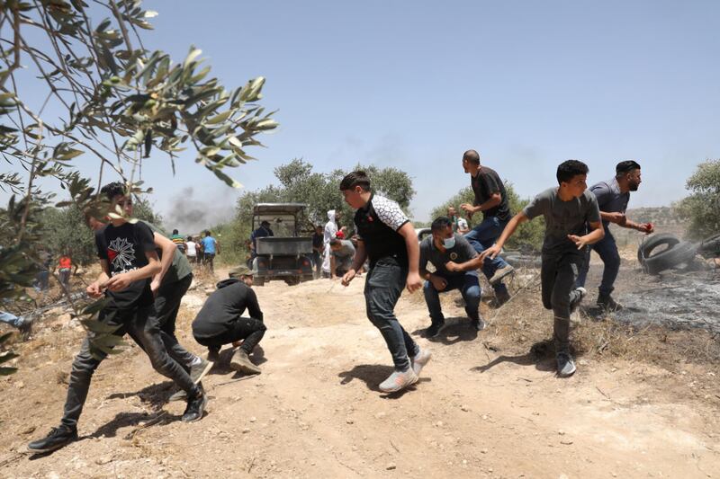 epa09233173 Palestinian protesters run to seek cover during clashes with Israeli troops after a protest against Israeli settlements at Beta village near the West Bank City of Nablus, 28 May 2021.  EPA/ALAA BADARNEH
