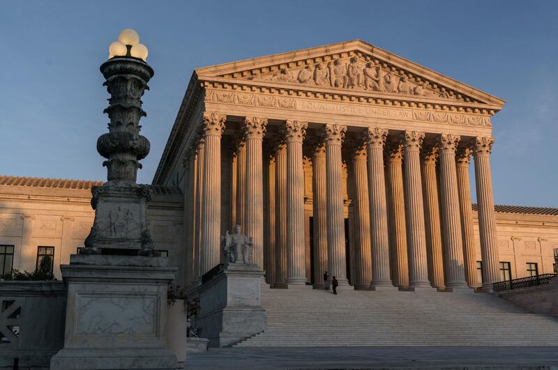 FILE - In this Nov. 6, 2020, file photo the Supreme Court is seen as sundown in Washington. The Supreme Court says it will continue to hear arguments by telephone through at least January because of the coronavirus pandemic. The courtâ€™s announcement Wednesday, Nov. 25, extends telephone arguments by a month. (AP Photo/J. Scott Applewhite, File)