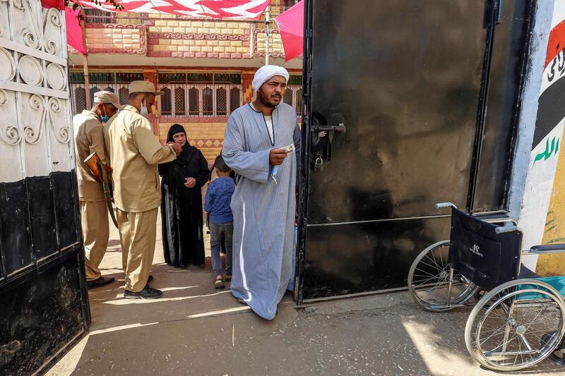 A voter holds his identification card and face mask as he enters a polling station in El Ayyat, south of the Egyptian capital, during the first stage of the lower house elections. AFP