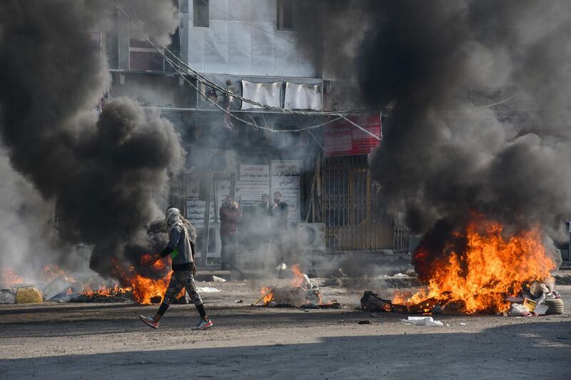 An Iraqi protester walks past burning tyres during clashes with police during anti-government demonstrations in the city of Nasiriyah in the Dhi Qar province in southern Iraq.  AFP