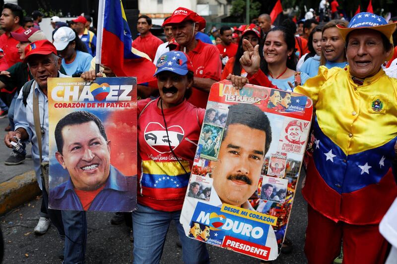 A woman holds placards with images of Venezuela's late President Hugo Chavez and Venezuela's President Nicolas Maduro during a rally in Caracas, Venezuela October 5, 2018. REUTERS/Marco Bello    NO RESALES. NO ARCHIVES