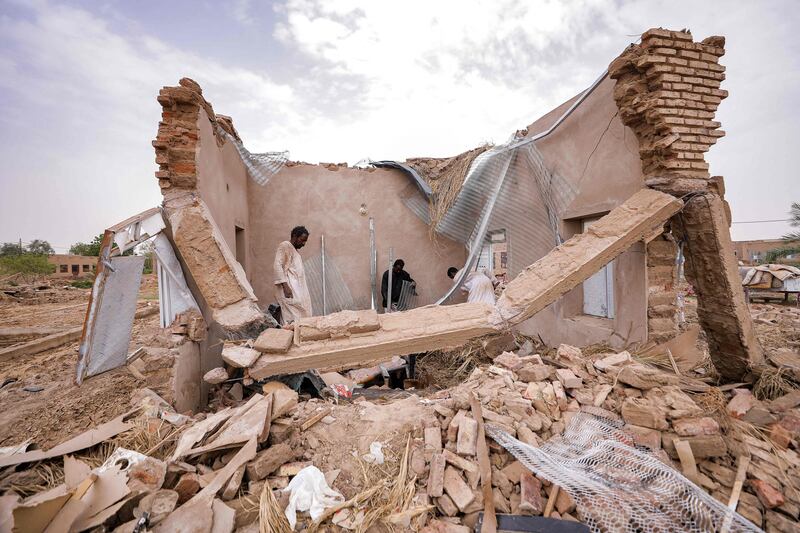 Men sift through the rubble of a destroyed house, after floods in the village of Makaylab, in Sudan's River Nile state. Photo: AFP