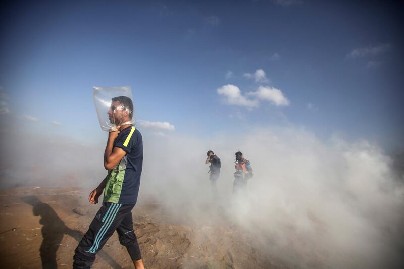 A man uses a plastic bag to protect himself from tear gas during clashes between Israeli troops and Palestinian protesters. EPA