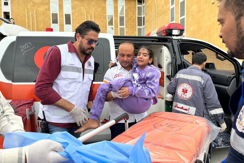 Egyptian paramedics transport a Palestinian child arriving from Gaza to an ambulance at the Rafah border crossing. AFP