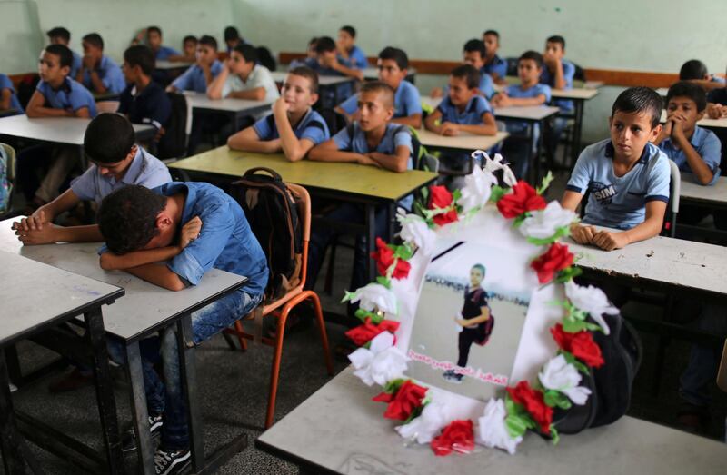 A picture of 12-year-old Palestinian boy Nassir Al Mosabeh, who was killed during a protest at the Israel-Gaza border fence, is seen on his table as his classmates react at a school, in Khan Younis in the southern Gaza Strip. Reuters