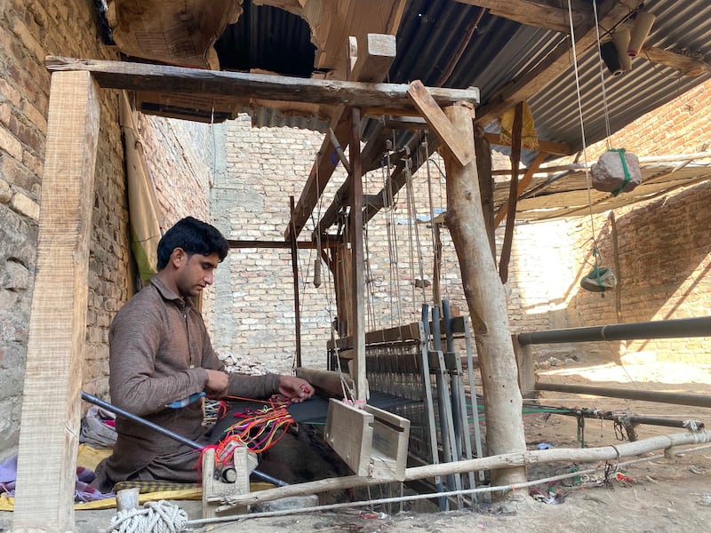 Shehzad, 25, weaves a shawl in the courtyard of his home