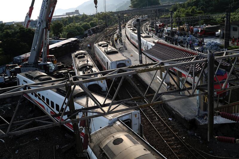 epa07110438 Rescuers use a crane to remove a derailed train at the site of the accident in Yilan, Taiwan, 22 October 2018. According to reports, at least 18 people died and about 160 were injured after a train carrying 366 people derailed and overturned on 21 October.  EPA/RITCHIE B. TONGO