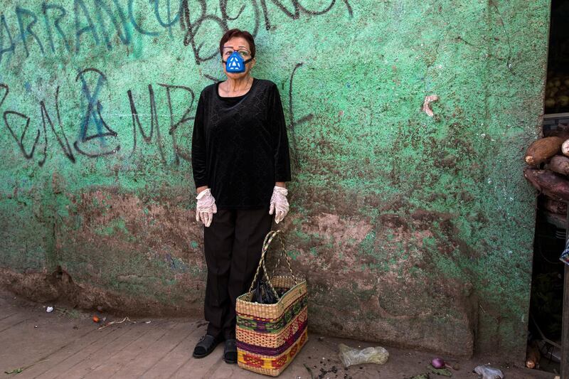 Carmen Villanueva, wearing a respirator mask and disposable gloves, waits for her daughter during a shopping trip to a popular market in Lima, Peru. AP Photo