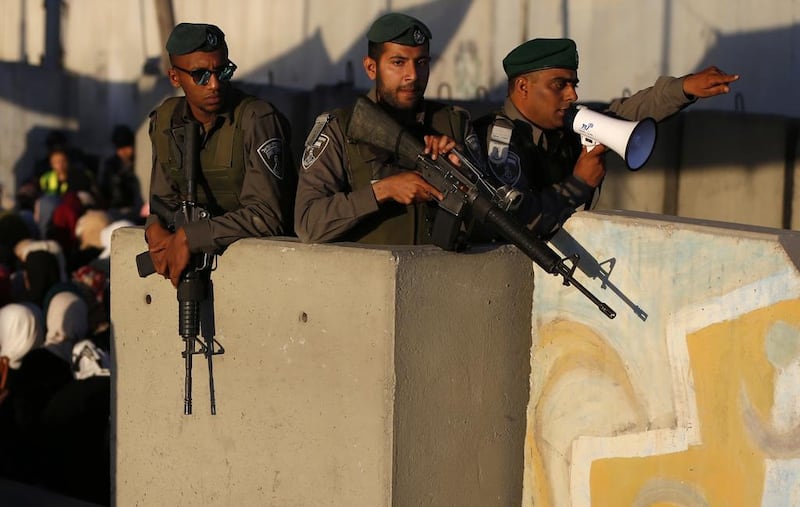Israeli border guards watch as Palestinians cross the Qalandia checkpoint from the West Bank into Jerusalem for the second Friday prayers of Ramadan at Al Aqsa mosque. Abbas Momani / AFP.