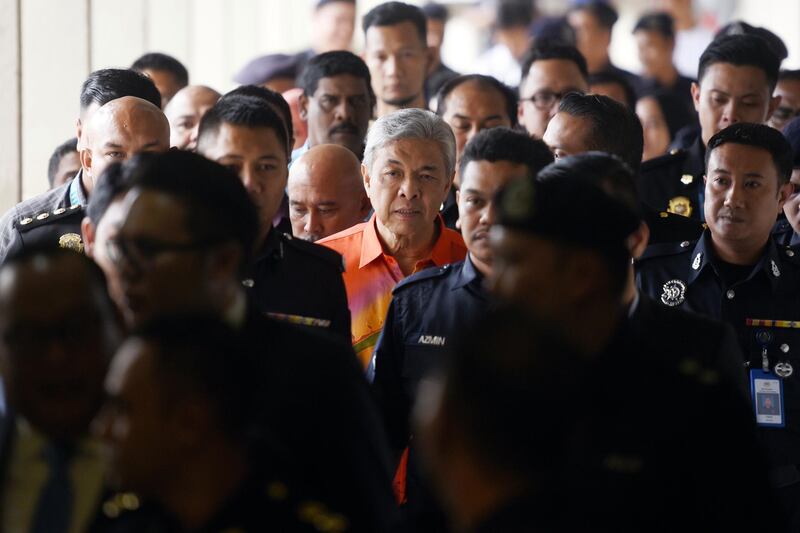 United Malays National Organization's (UMNO) President Ahmad Zahid Hamidi, center, walks out of court room at Kuala Lumpur High Court in Kuala Lumpur, Malaysia, Friday, Oct. 19, 2018. Zahid has been charged with abuse of power, corruption and money laundering involving millions of dollars in another graft investigation against the leaders ousted in shock election results earlier this year. (AP Photo/Yam G-Jun)