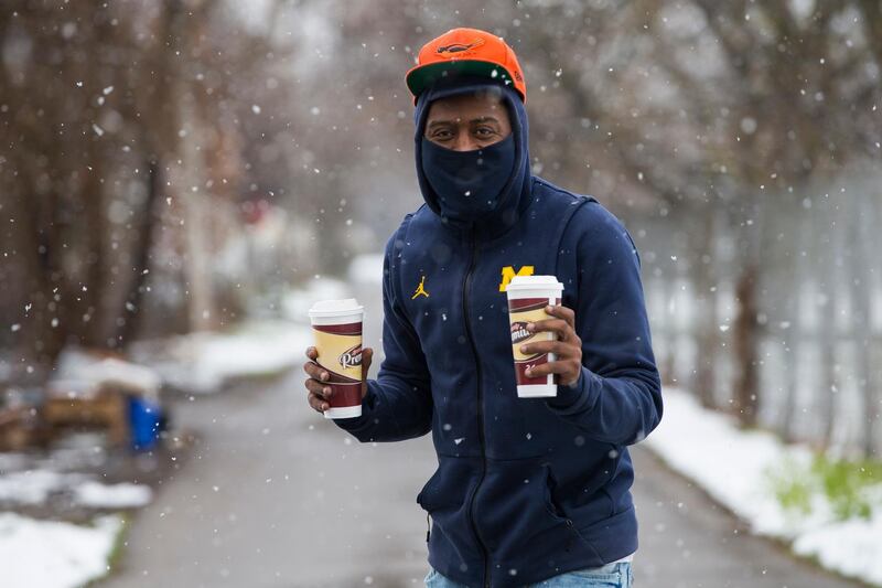 Samuel Rhodes starts his day with coffee and his personal protective mask during the coronavirus outbreak as a light snow falls in the Edgewater neighborhood on Friday, April 17, 2020, in Rockford, Ill. (Scott P. Yates/Rockford Register Star via AP)