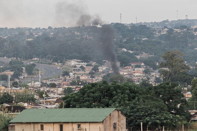 A police helicopter hovering over Bhambayi township as smoke rises in Durban. AFP