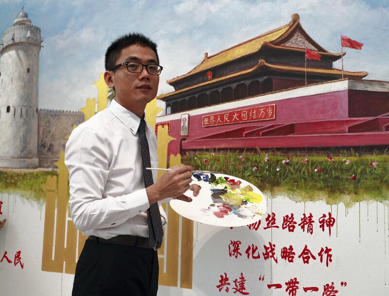 Abu Dhabi, U.A.E., July 17, 2018.   The Launch of China Week at Manarat Al Saadiyat with guests of honor, Noura Al Kaabi, Minister of Culture and Knowledge Development and Ni Jian, Ambassador of China.--  Chinese artist and teacher, Jack Lee infront of his collaborative painting with Emirati Artist, Mohammed Mandi of the Tiananmen Square entrance and the Qasr Al hosn Fort. 
 Victor Besa / The National
Section:  NA
Reporter:  John Dennehy