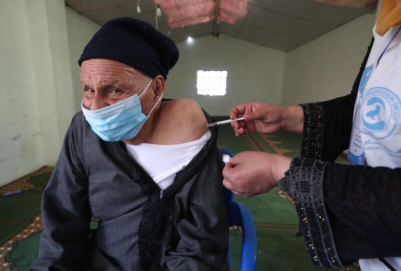 A medic from the "Syria Immunization Group" NGO administers the COVID-19 AstraZeneca vaccine to a patients with chronic diseases, at a camp for the internally displaced near Marret Misrin town, in the north of Syria's rebel-held Idlib governorate, on June 14, 2021. / AFP / OMAR HAJ KADOUR
