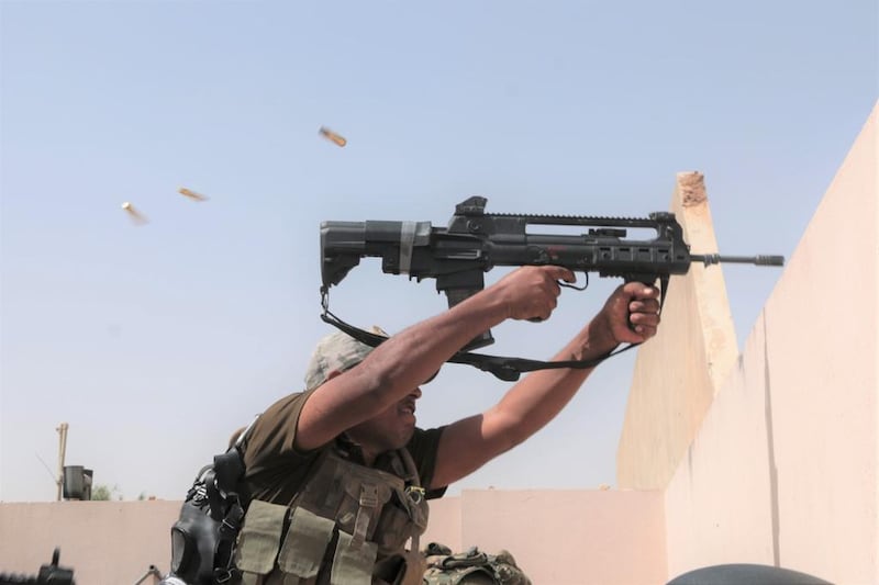 An Iraqi soldier sprays fire at an ISIS position across the road in west Mosul. Florian Neuhof / The National