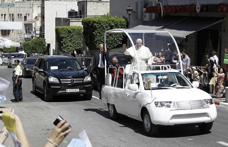 Pope Francis waves to the crowd from inside his pope-mobile on his way to Manger Square to celebrate an open air mass on May 25, 2014 in the West Bank Biblical town of Bethlehem. Pope Francis is expected to begin in Bethlehem the most sensitive part of his three-day Middle East tour aimed at forging regional peace and easing an age-old rift within Christianity. Jaafar Ashtiyeh/AFP Photo