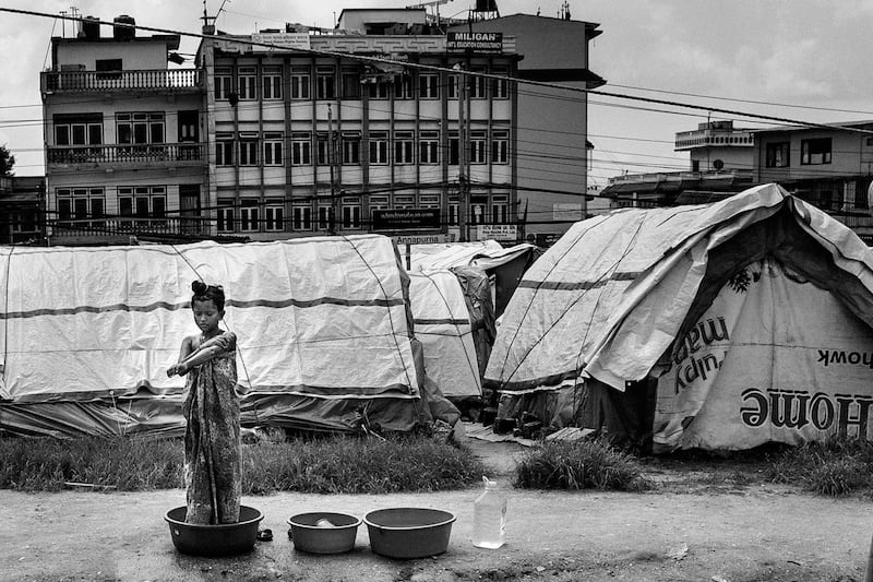 A young girl bathes using plastic buckets in the Chhuchepati temporary camp on the outskirts of Kathmandu. Photo: Omar Havana/ Xposure Photo Festival