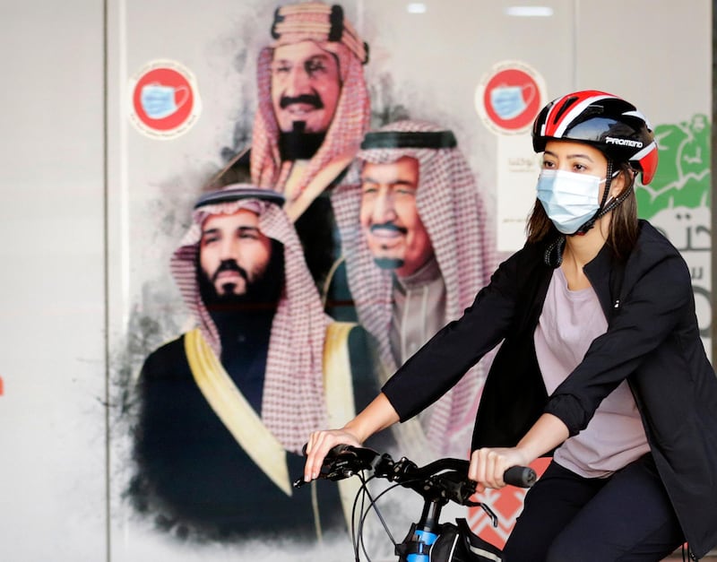 Sawsan Abdel Fattah, a Saudi cyclist and member of the Brave team, rides past a banner depicting King Salman, Crown Prince Mohammed bin Salman, and Saudi Arabia's founder King Abdulaziz, in Jeddah. AP