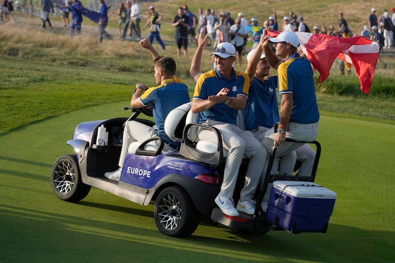 European team members celebrate as they ride a buggy to the 18th green after winning the Ryder Cup. Getty