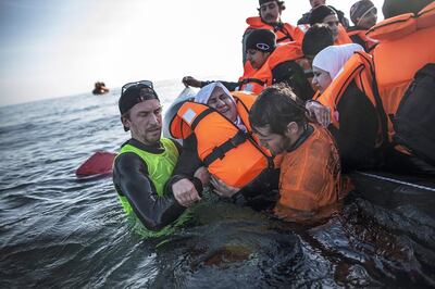 A Syrian refugee is helped by volunteers to leave a sinking dinghy at a beach on the south-eastern island of Lesbos in 2016. AP Photo